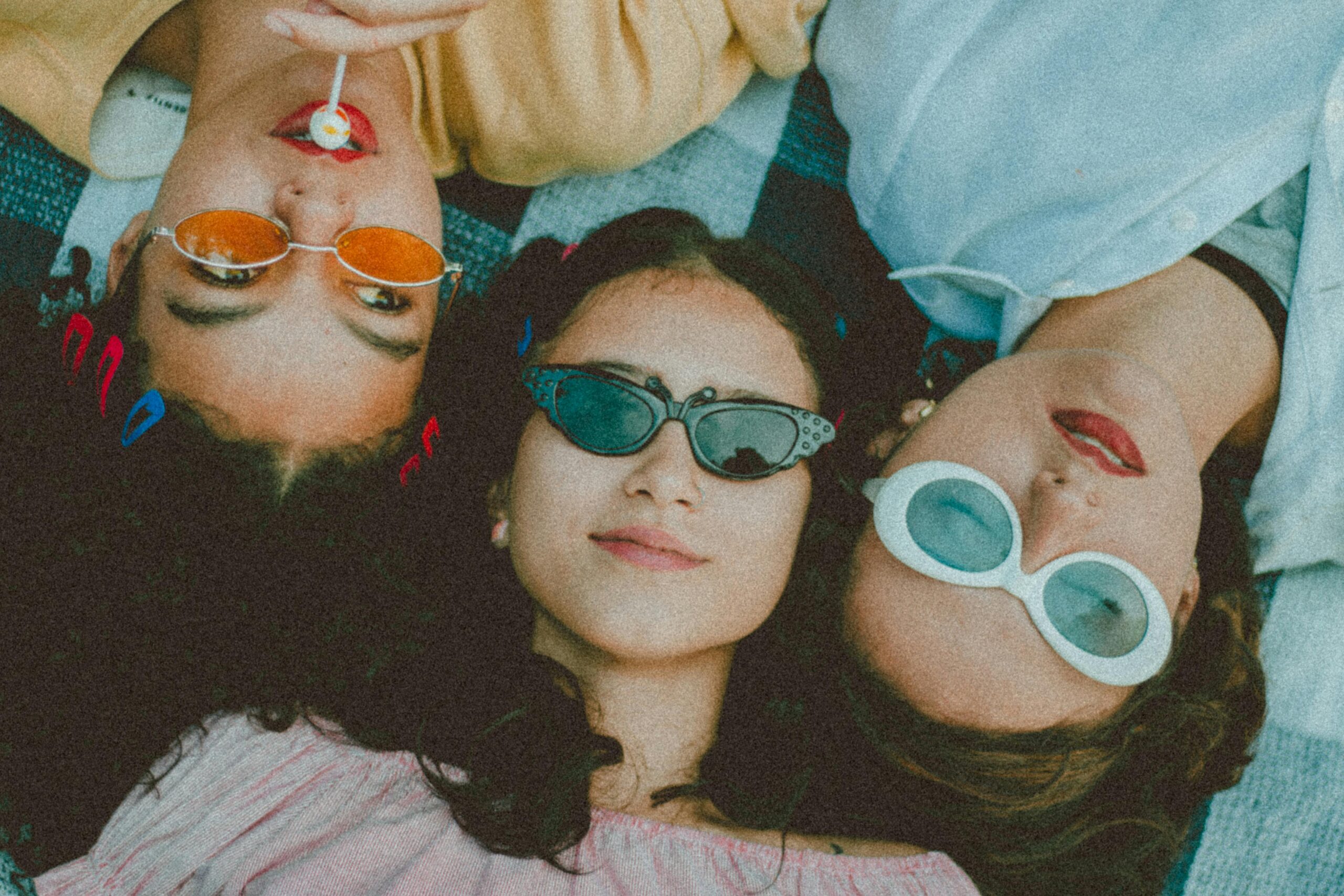 taking a mental health day - Three girls laying side by side on a blanket, wearing sunglasses.