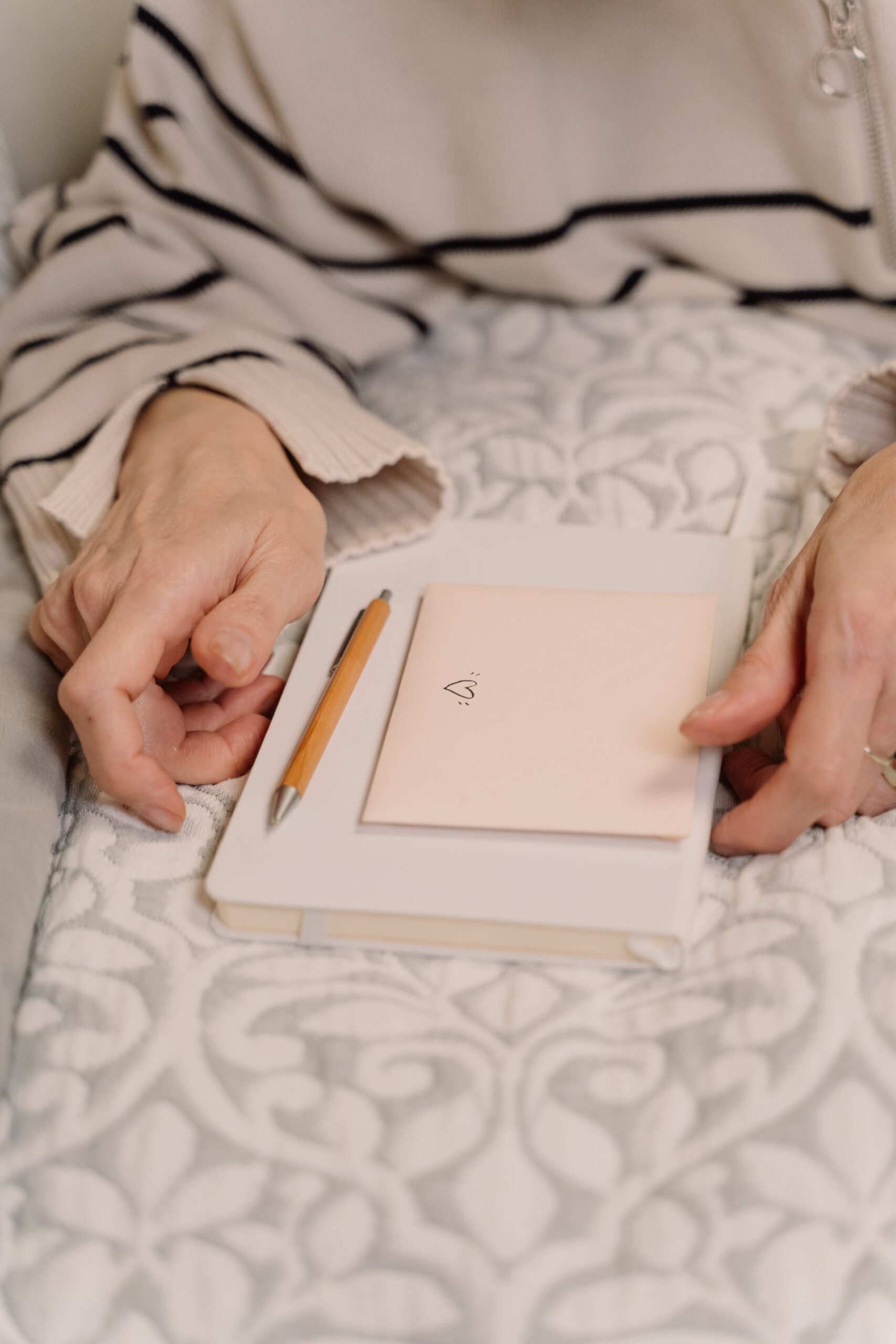 Valentine's 2024 - A person writing in a notebook on a bed with a love letter on top.