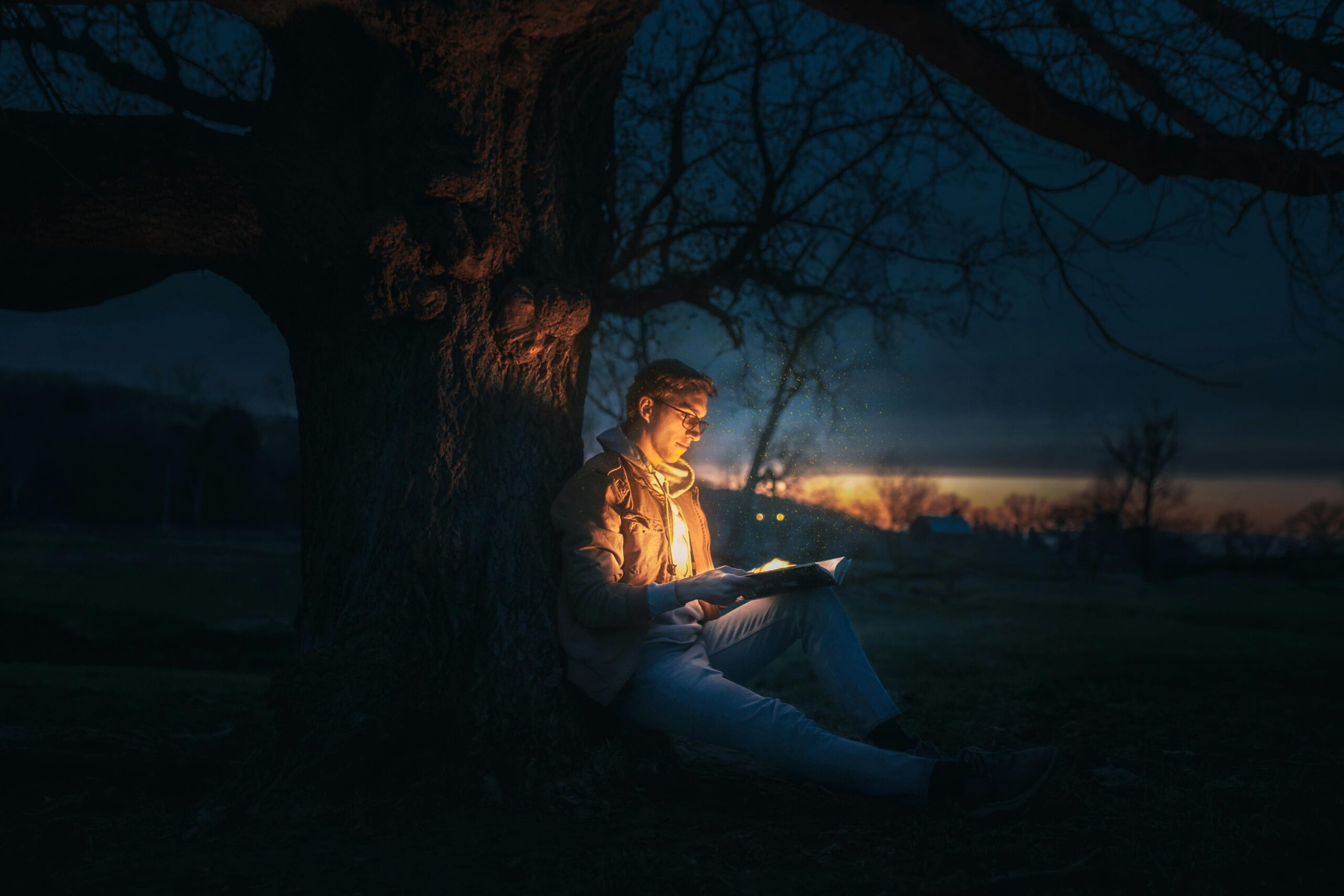 A court of thorns and roses review - A man enjoying a peaceful moment under a tree, engrossed in a book, lost in the world of words.