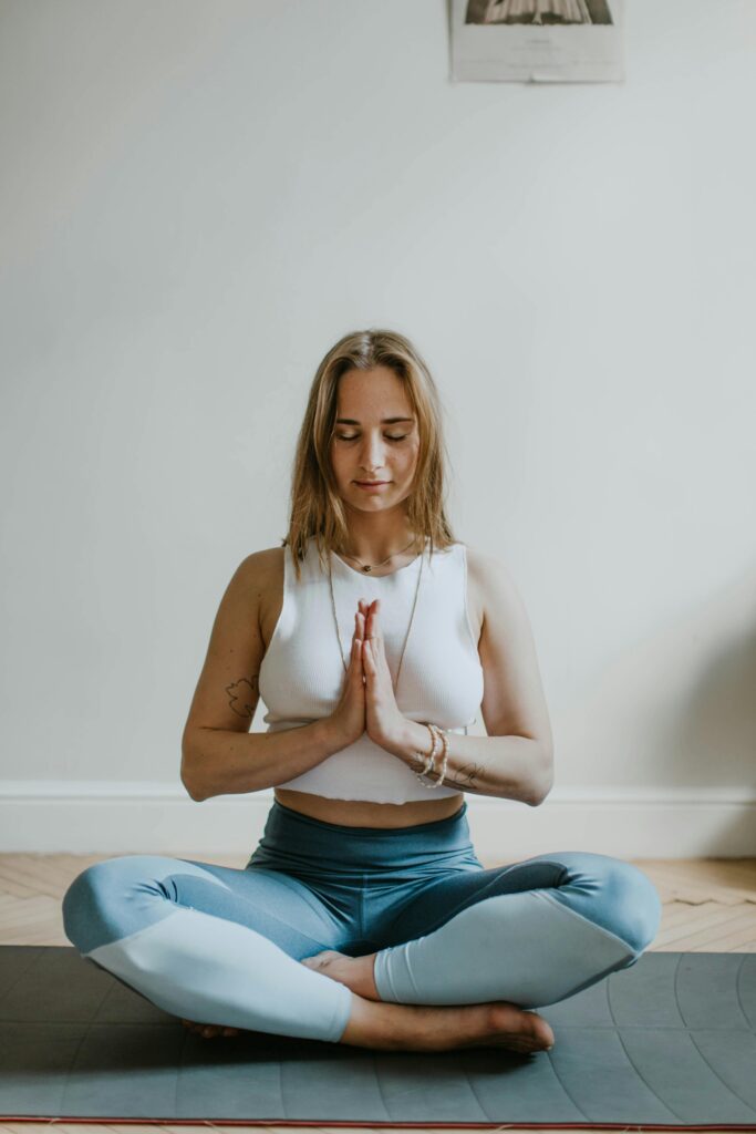 Embrace your femininity - A woman peacefully sitting in a yoga pose, finding balance and serenity in her practice.