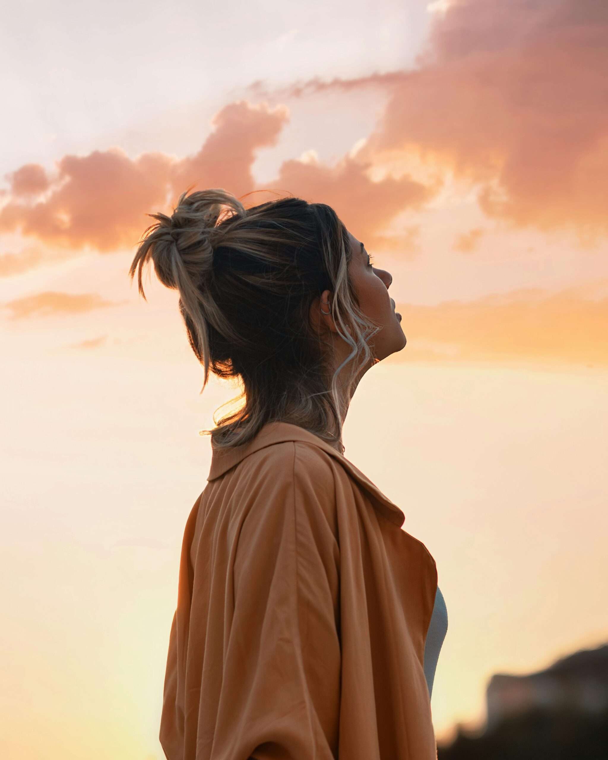 affirmations for anxiety - Woman standing in front of a vibrant sunset, silhouette against the colorful sky.