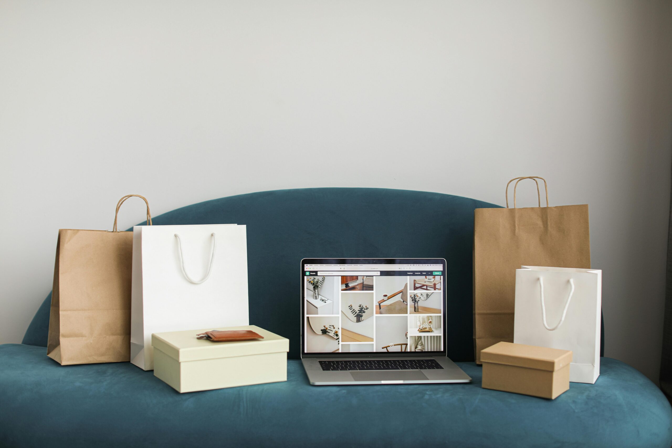 benefits of thrifting - Shopping bags and boxes surrounding a open laptop on a couch. 