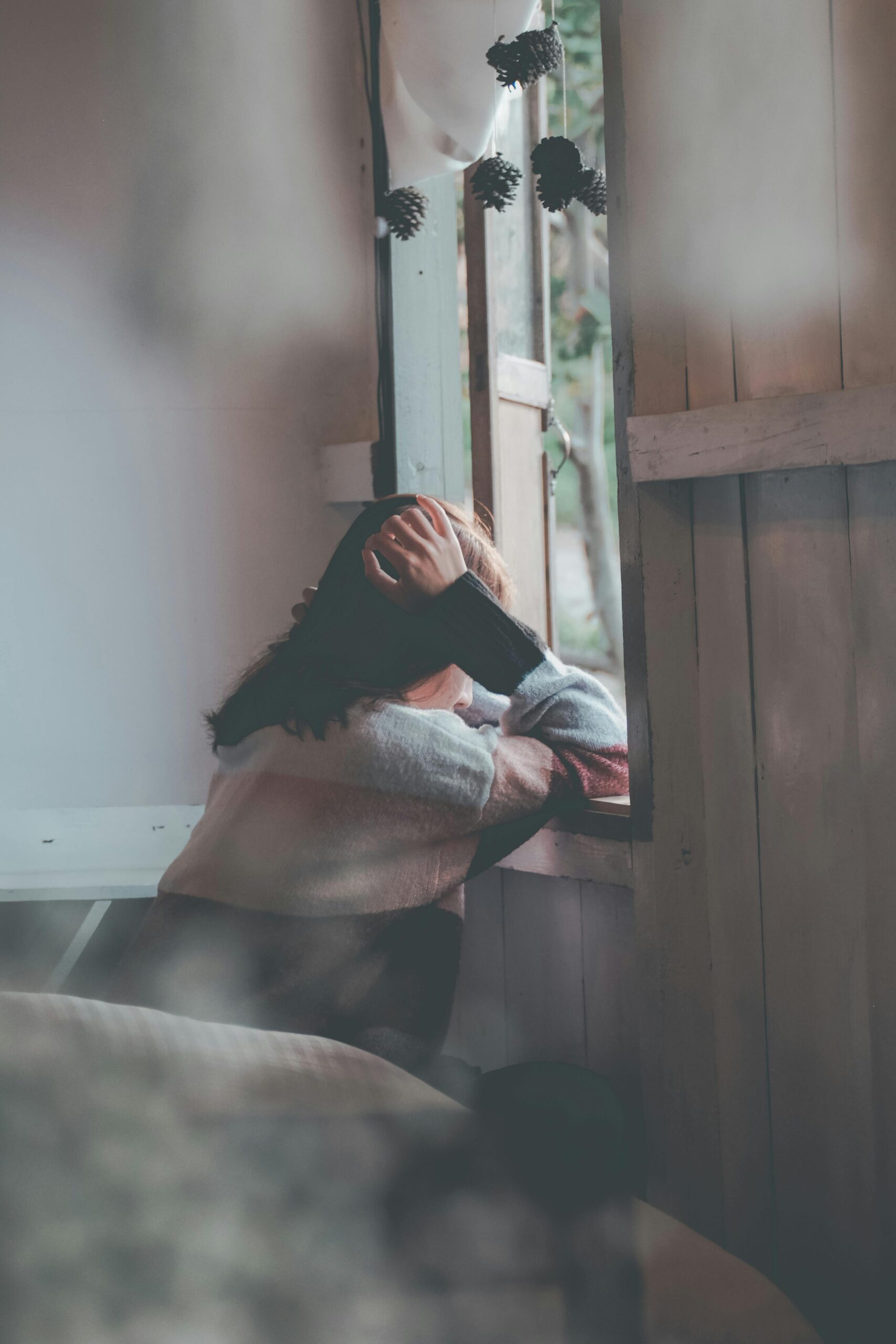 Life transitions - An image of a woman sitting on the edge of a bed, appearing distressed with her head resting in her hands.