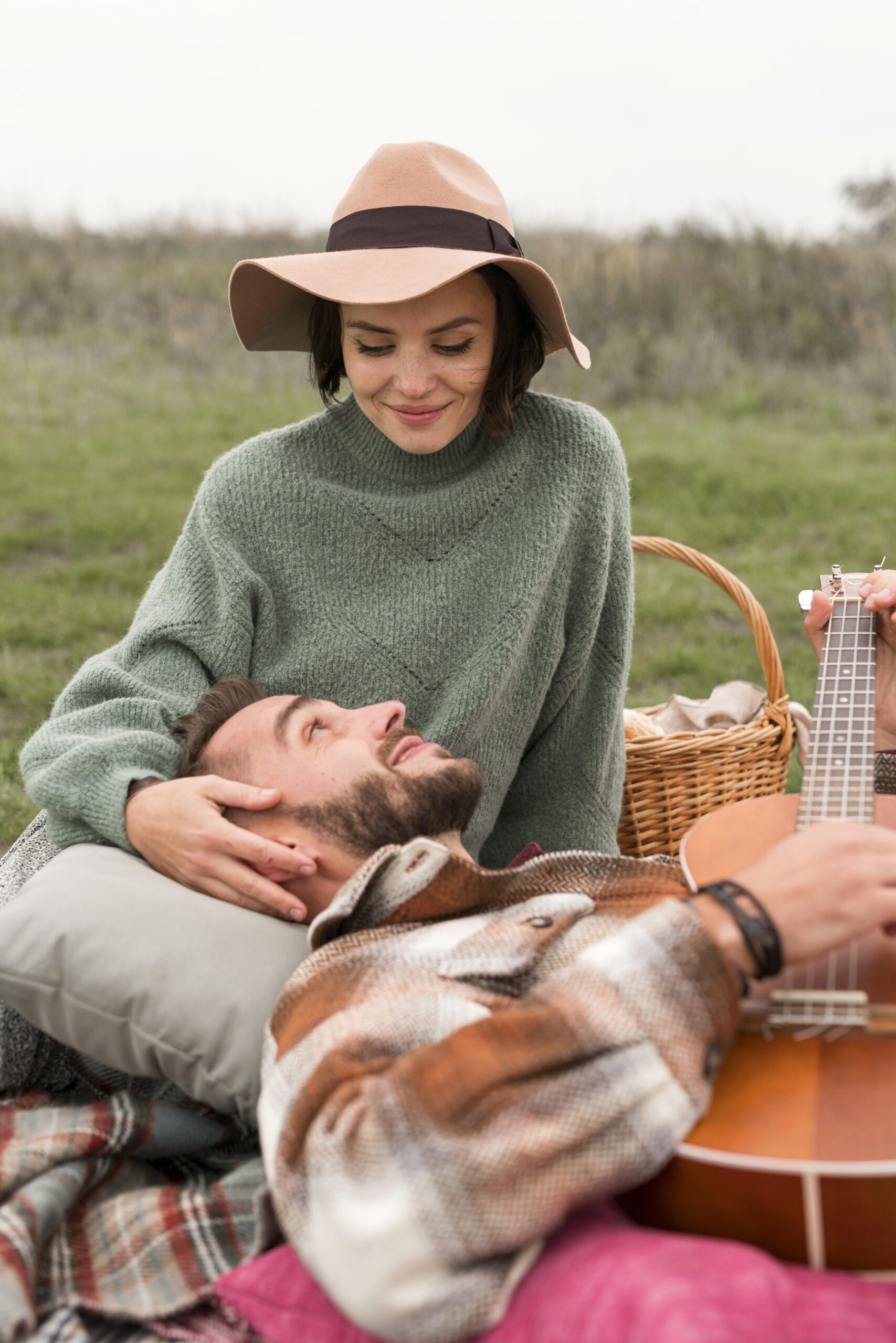 Grab your picnic blanket - Man playing guitar and playing in womans lap at a picnic 