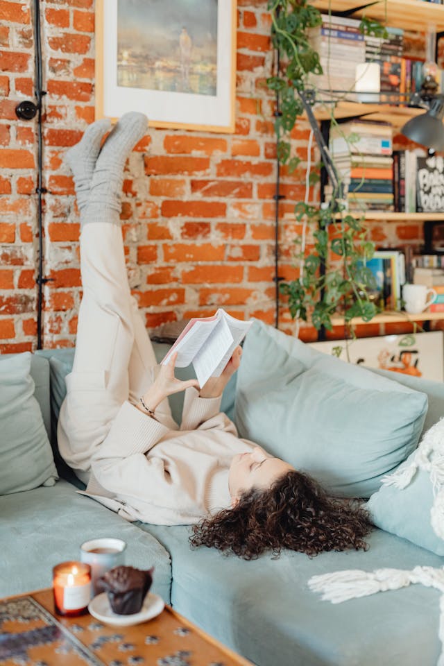 get cozy - woman on the couch with her feet crossed and up against the wall