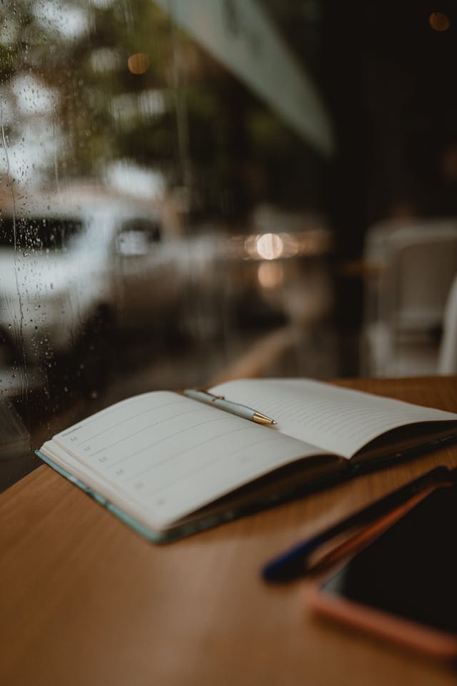 Types of journaling: journal sitting on a desk next to a rain covered window